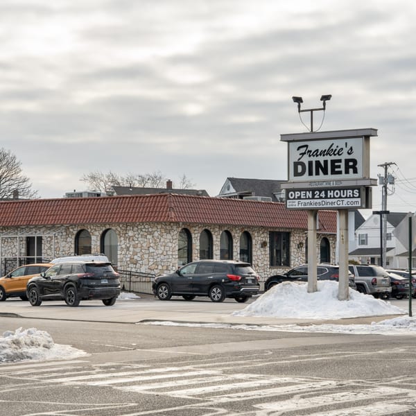 Frankie's Diner exterior with a stone facade, red roof, and large sign, surrounded by cars and snow.