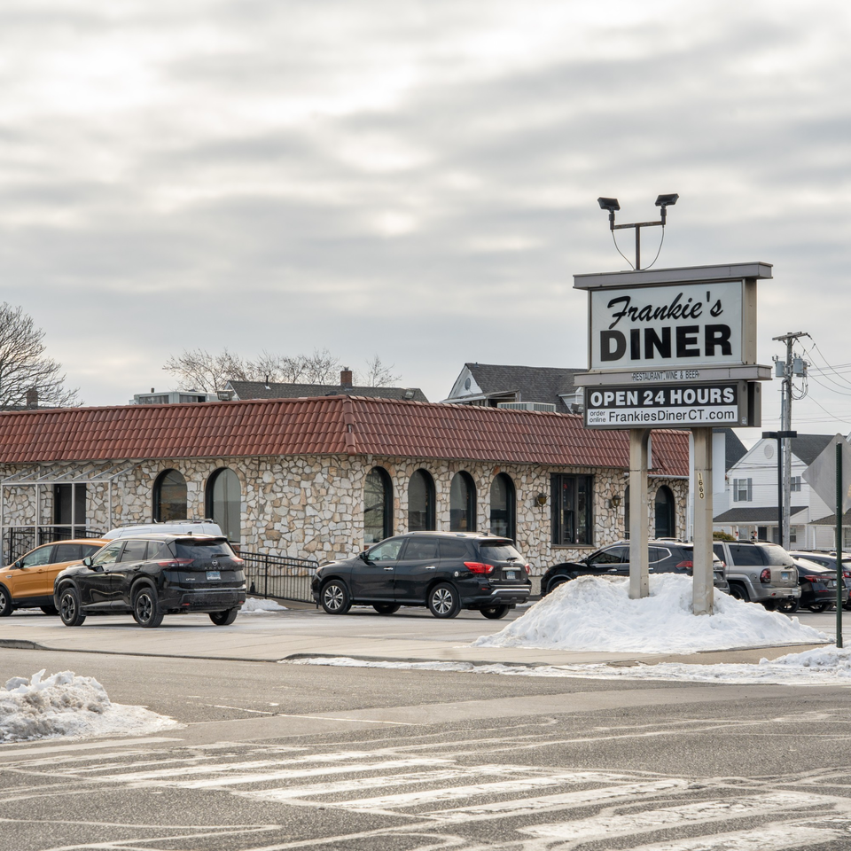 Frankie's Diner exterior with a stone facade, red roof, and large sign, surrounded by cars and snow.